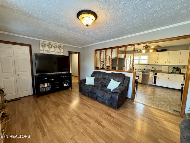 living room with crown molding, ceiling fan, a textured ceiling, and light hardwood / wood-style flooring