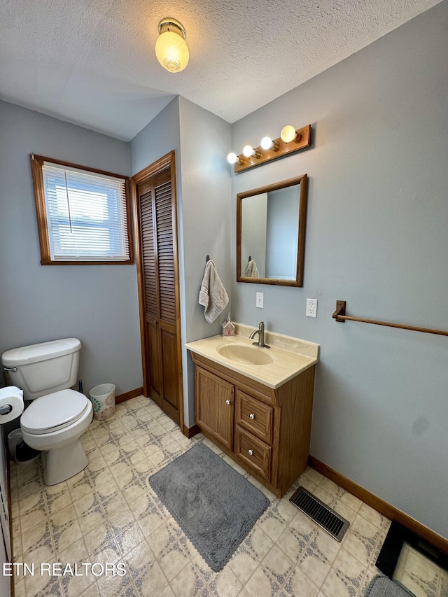 bathroom featuring vanity, toilet, and a textured ceiling