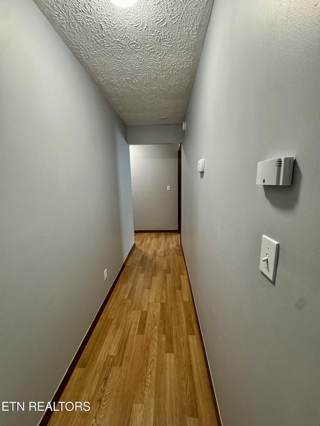 hall featuring light hardwood / wood-style floors and a textured ceiling