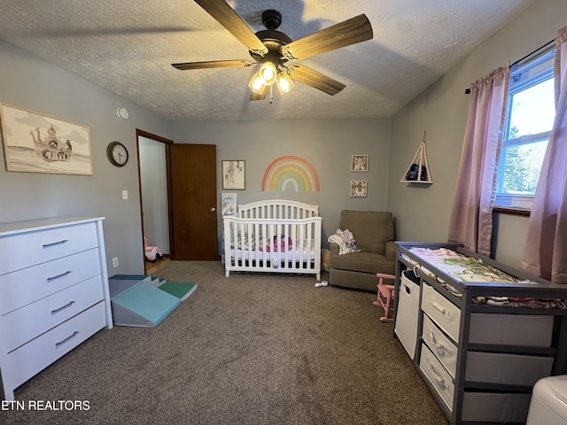 carpeted bedroom with ceiling fan, a textured ceiling, and a crib