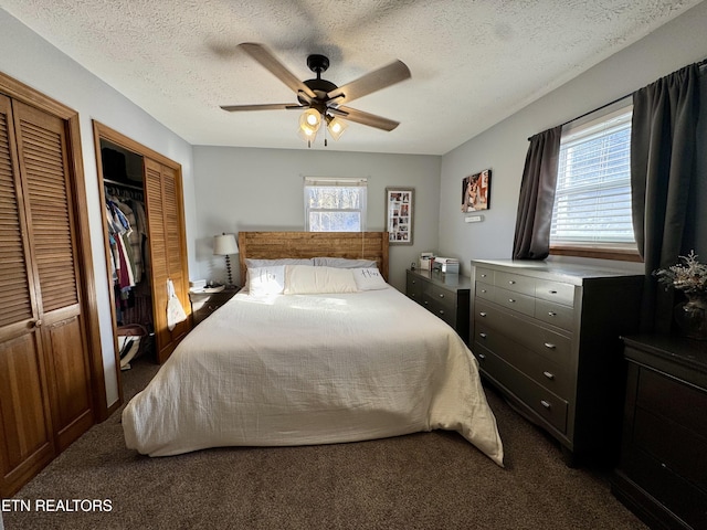 carpeted bedroom with multiple windows, ceiling fan, multiple closets, and a textured ceiling