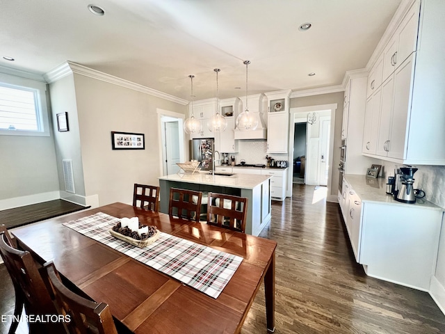 dining area featuring dark wood-type flooring, ornamental molding, and sink