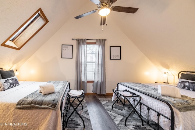 bedroom with dark wood-type flooring, vaulted ceiling with skylight, and ceiling fan