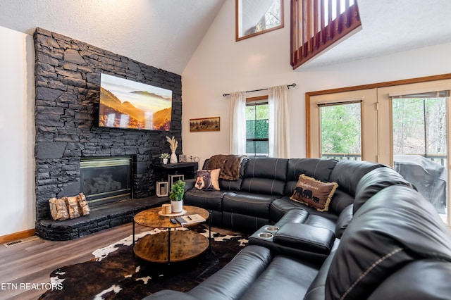 living room with wood-type flooring, lofted ceiling, a textured ceiling, and a fireplace