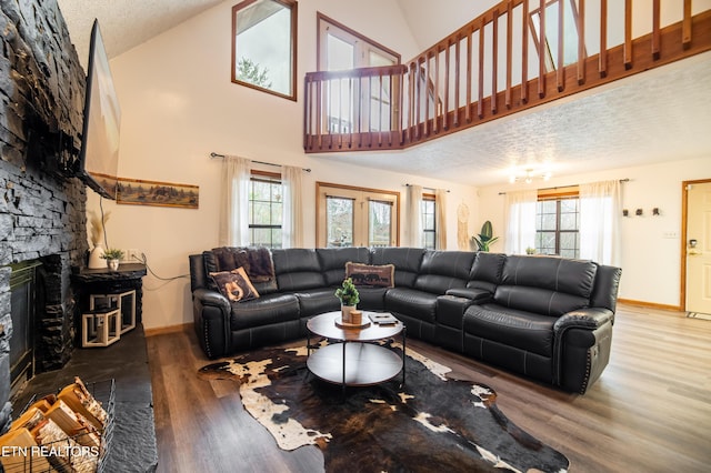 living room featuring plenty of natural light, a stone fireplace, hardwood / wood-style floors, and a textured ceiling