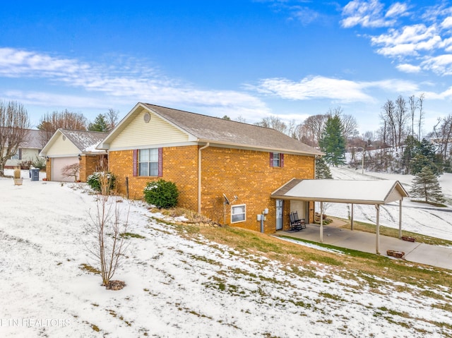 view of snow covered exterior featuring a garage and a carport