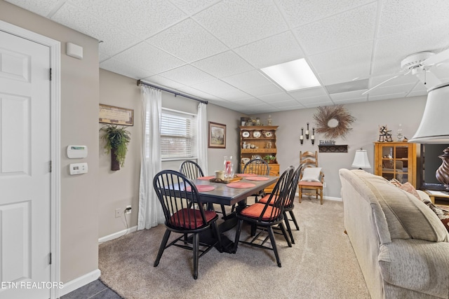 carpeted dining area with a drop ceiling and ceiling fan