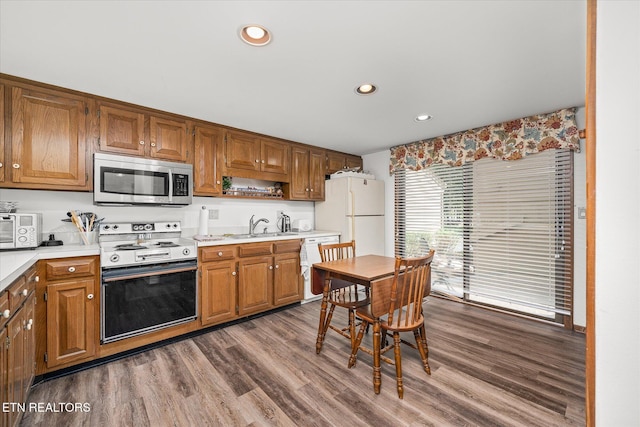 kitchen featuring white appliances, hardwood / wood-style flooring, and sink