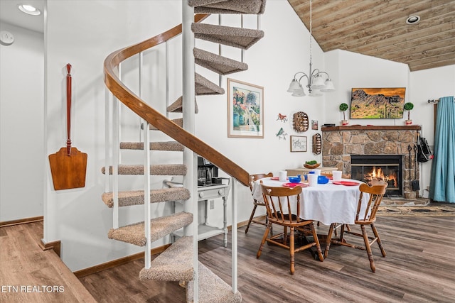 dining space with hardwood / wood-style floors, wooden ceiling, vaulted ceiling, a notable chandelier, and a fireplace