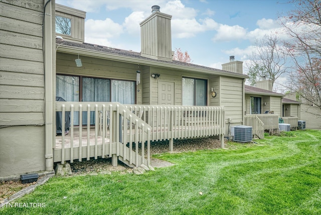 back of property with a yard and central AC