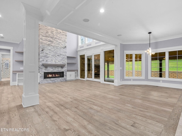 unfurnished living room featuring a notable chandelier, light wood-type flooring, crown molding, and a fireplace