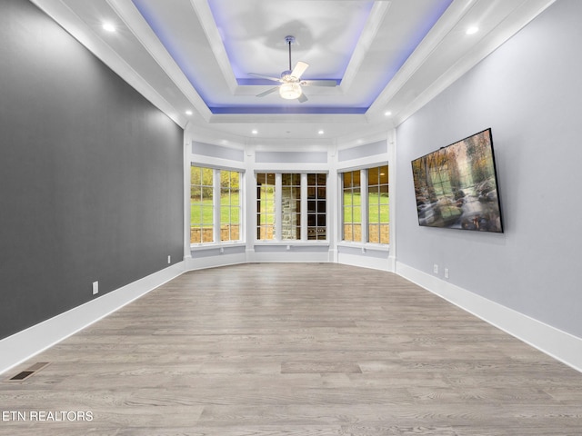 spare room featuring a raised ceiling, ceiling fan, and light wood-type flooring