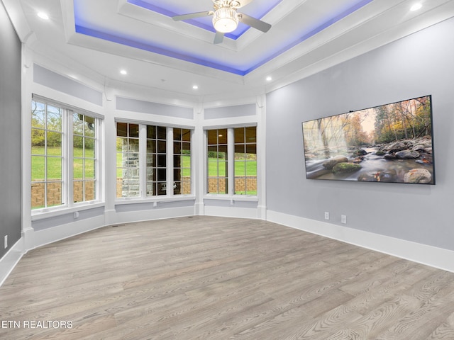 interior space with a raised ceiling, ceiling fan, and light hardwood / wood-style floors