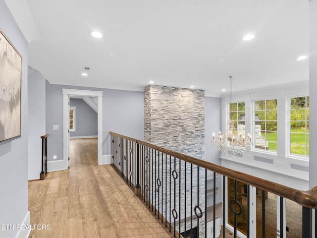 hallway featuring light hardwood / wood-style flooring, crown molding, and a chandelier