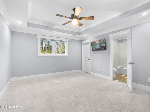 unfurnished bedroom featuring ornamental molding, ceiling fan, ensuite bathroom, and a tray ceiling