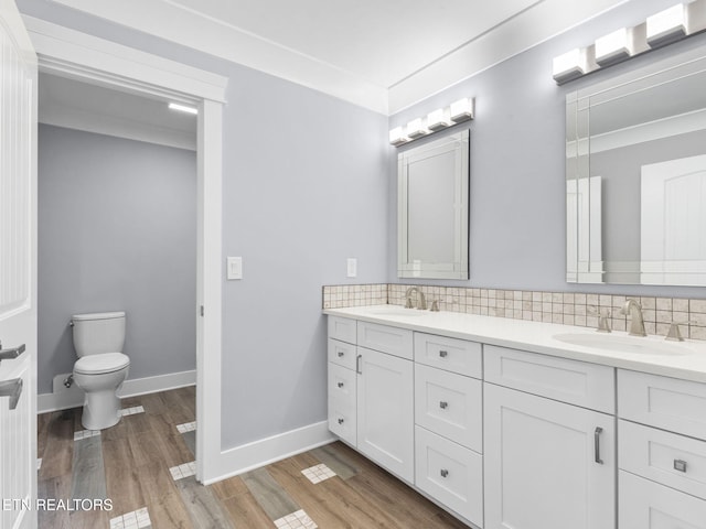 bathroom featuring crown molding, hardwood / wood-style flooring, backsplash, and vanity