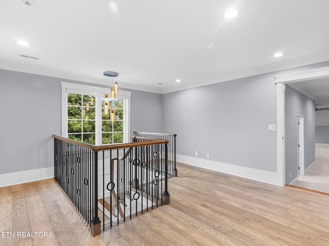 corridor with a chandelier, light hardwood / wood-style floors, and crown molding