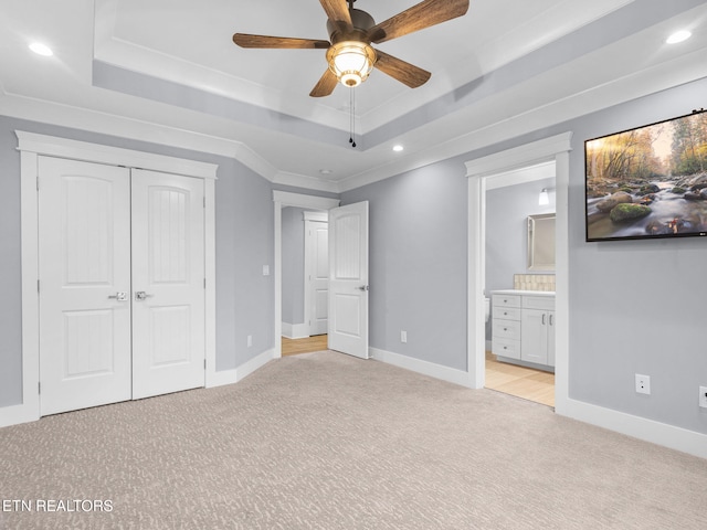 unfurnished bedroom with ceiling fan, a tray ceiling, ornamental molding, and light colored carpet