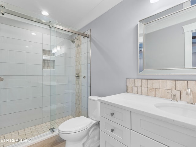 bathroom featuring toilet, backsplash, walk in shower, and vanity