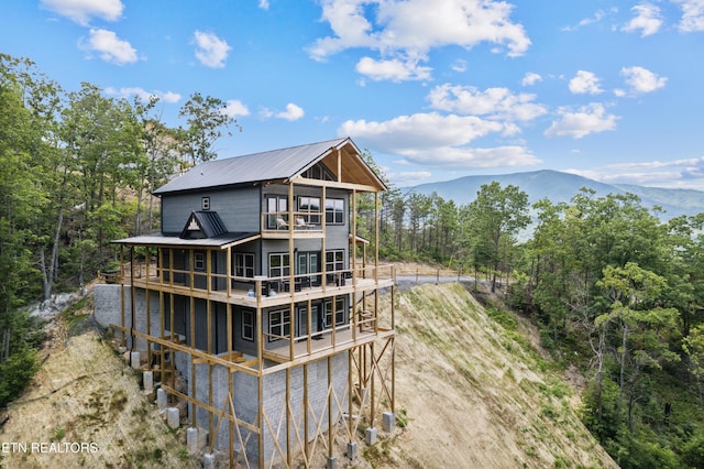 rear view of property with a balcony and a mountain view