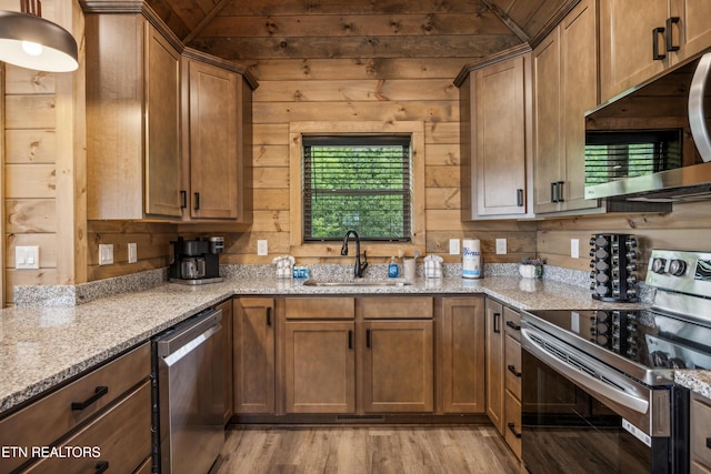 kitchen featuring vaulted ceiling, stainless steel appliances, light stone countertops, and sink