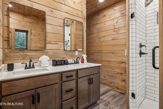 bathroom featuring hardwood / wood-style flooring, a shower with door, wood walls, and vanity