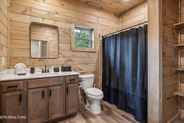 bathroom with hardwood / wood-style floors, wood walls, toilet, a shower with shower curtain, and vanity