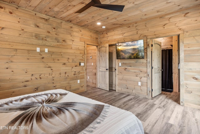 bedroom with light hardwood / wood-style floors, wooden ceiling, ensuite bath, and wood walls