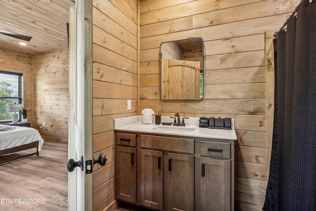 bathroom featuring hardwood / wood-style flooring, wooden walls, and vanity