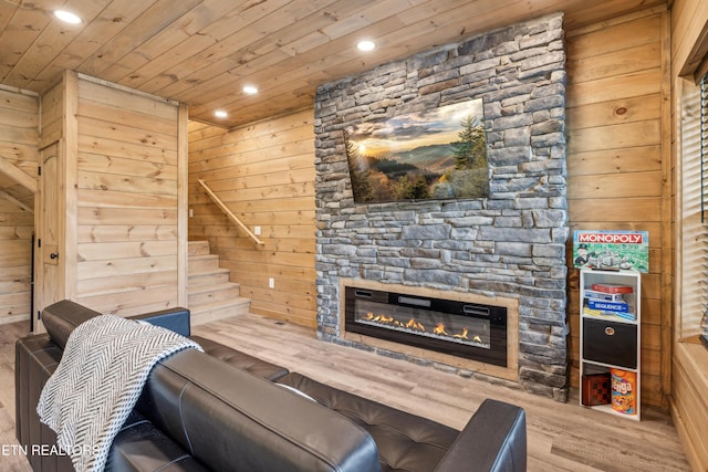 living room featuring wood ceiling, a stone fireplace, and wood walls