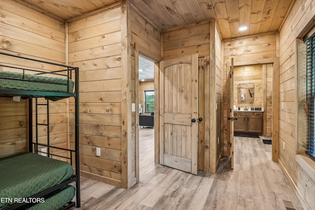 bedroom with wooden walls, light hardwood / wood-style flooring, and wooden ceiling