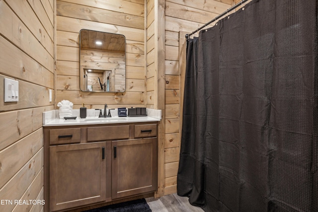 bathroom with walk in shower, wooden walls, vanity, and hardwood / wood-style flooring