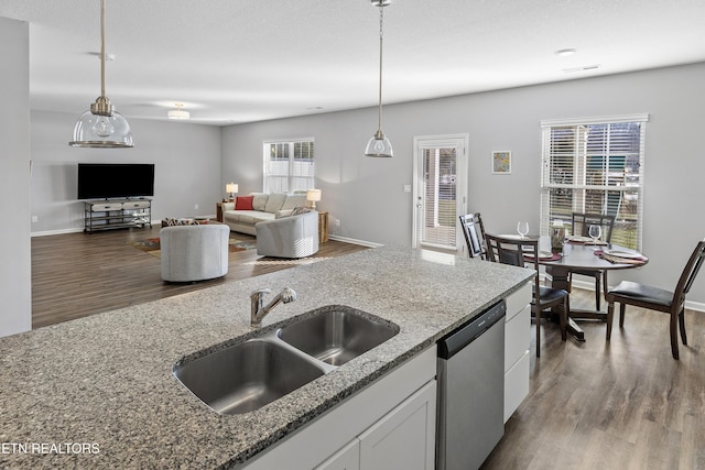 kitchen with sink, stone counters, white cabinetry, dishwasher, and hanging light fixtures