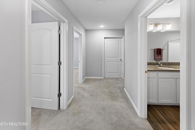 corridor featuring sink and light colored carpet