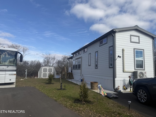 view of side of property with ac unit, a storage unit, and a yard