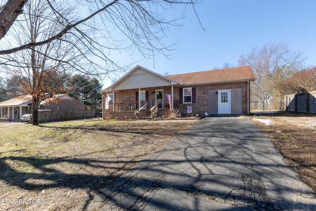 ranch-style house featuring covered porch and a front lawn