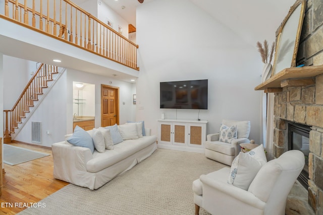 living room with wood-type flooring, a fireplace, sink, and a high ceiling