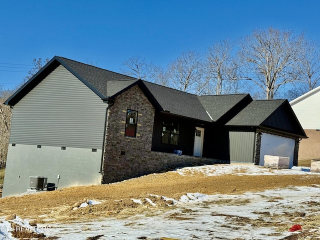 view of snowy exterior featuring a garage and central air condition unit