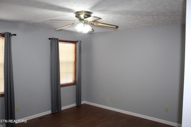 empty room with a textured ceiling, ceiling fan, and dark hardwood / wood-style floors