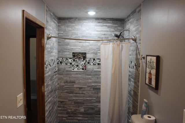 bathroom with a shower with shower curtain and a textured ceiling