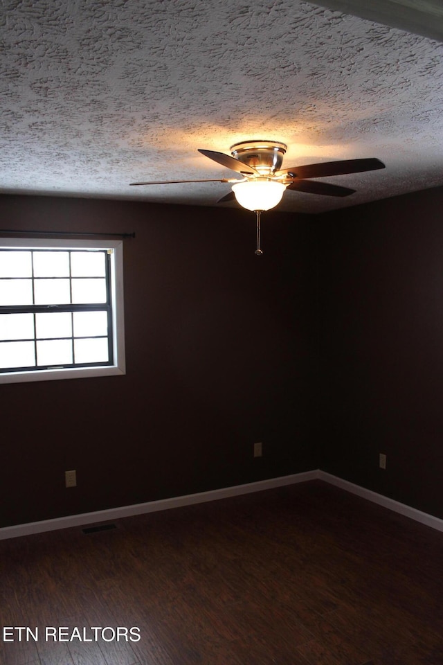 unfurnished room featuring a textured ceiling, dark wood-type flooring, and ceiling fan