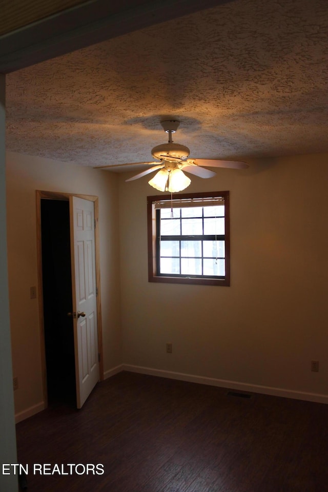 empty room featuring dark hardwood / wood-style flooring, a textured ceiling, and ceiling fan