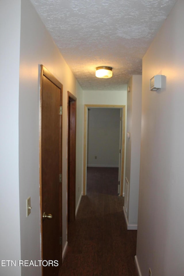 corridor featuring a textured ceiling and dark hardwood / wood-style floors