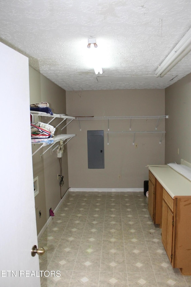 clothes washing area featuring a textured ceiling, washer hookup, electric panel, and cabinets