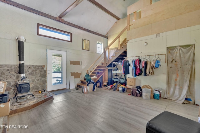 miscellaneous room with hardwood / wood-style floors, high vaulted ceiling, and a wood stove