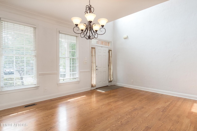 unfurnished dining area with light wood-type flooring, crown molding, and an inviting chandelier