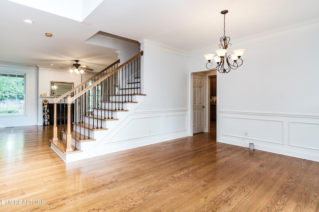 interior space with wood-type flooring, ceiling fan with notable chandelier, and ornamental molding