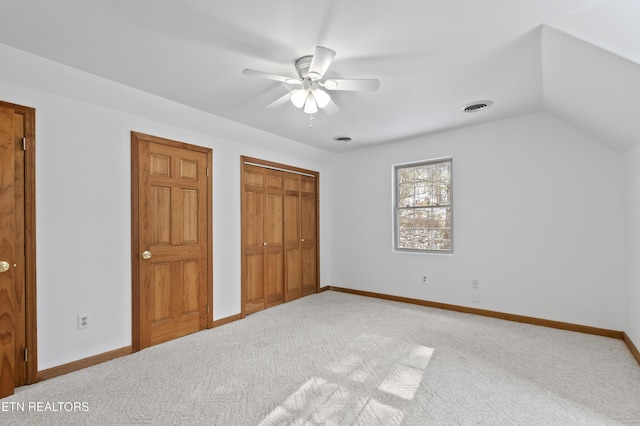 unfurnished bedroom with ceiling fan, multiple closets, lofted ceiling, and carpet flooring