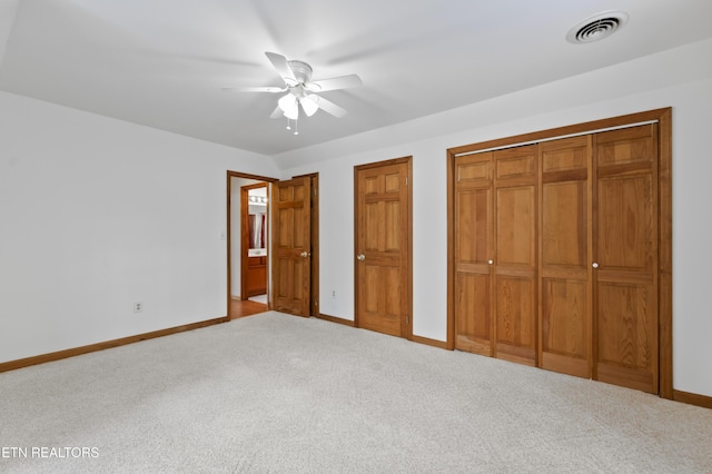 unfurnished bedroom featuring ceiling fan, two closets, and light carpet