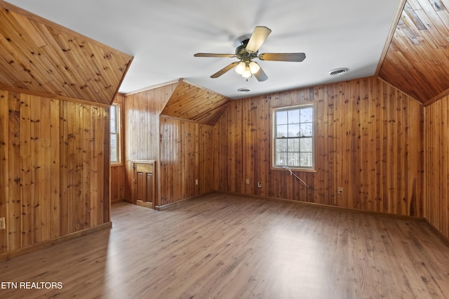 bonus room featuring ceiling fan, vaulted ceiling, wood walls, and hardwood / wood-style flooring